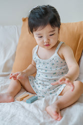 Toddler sitting on bed and playing with blocks in Avauma Blue Herb picnic tank top set